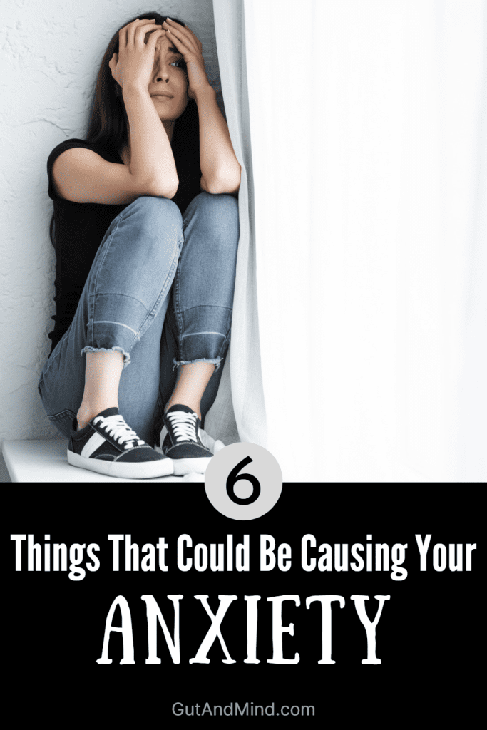 Overwhelmed/anxious woman sitting on a window sill with the text below her, "6 things that could be causing your anxiety"